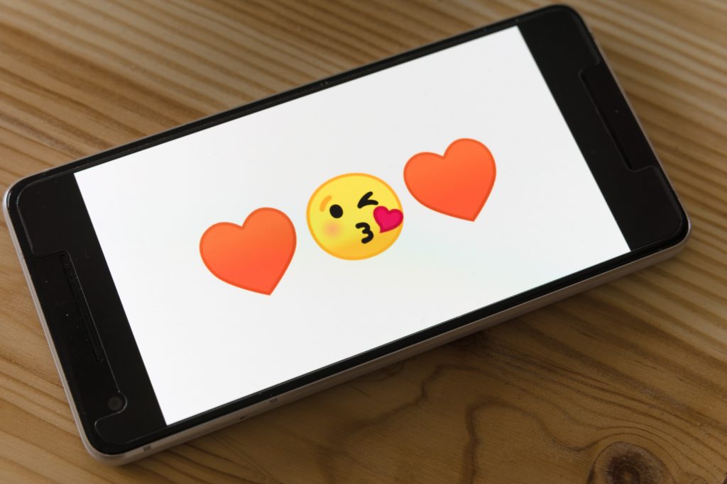 Slika telefona z emojijem srčka in poljuba